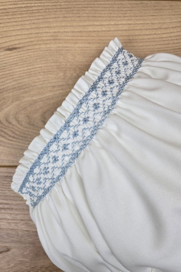 BRAGUITA VIELLA EN CRUDO BORDADA EN PUNTO SMOCK AZUL INGLÉS. ARTESANÍA CARMINA. INVIERNO 26.